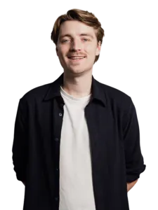 Een jonge man met kort lichtbruin haar staat met gekruiste armen en glimlacht. Hij draagt een donkergrijze trui en een smartwatch op zijn linkerpols. 