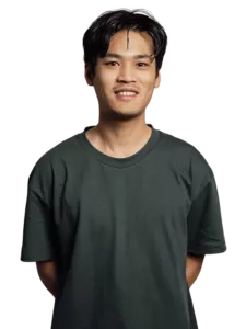 Jonge man met zwart haar in een zwart shirt kijkt ontspannen naar links met zijn handen in zijn zakken
