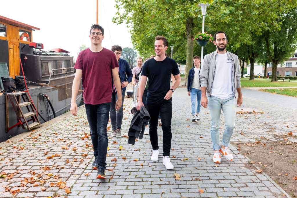 Drie oprichters van Stijlbreuk lopen voorop langs de kade, met de collega's erachter, langs een boot.