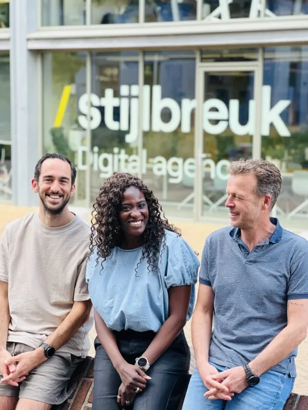 Drie lachende mensen voor een activeringshuis met 